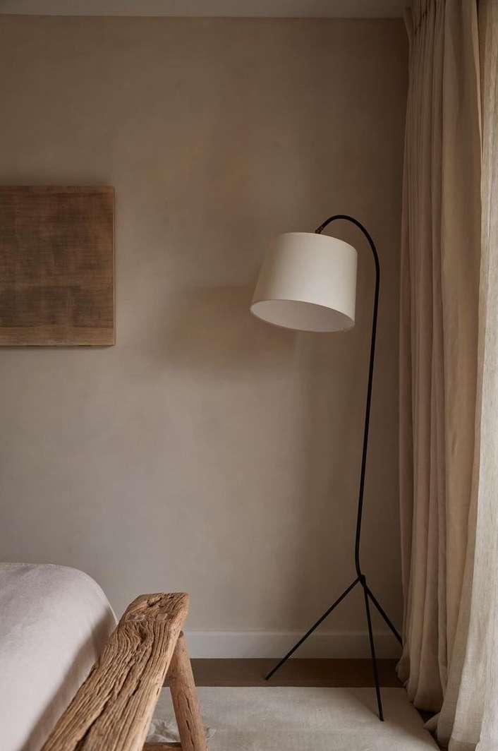 Minimalist interior with a modern arc floor lamp, wood accent table, neutral color palette, and a serene, comfortable bedroom environment.