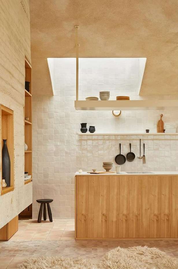 Modern kitchen interior featuring light wood cabinets, a skylight, tiled backsplash, and minimalist decor, creating a bright, spacious atmosphere.