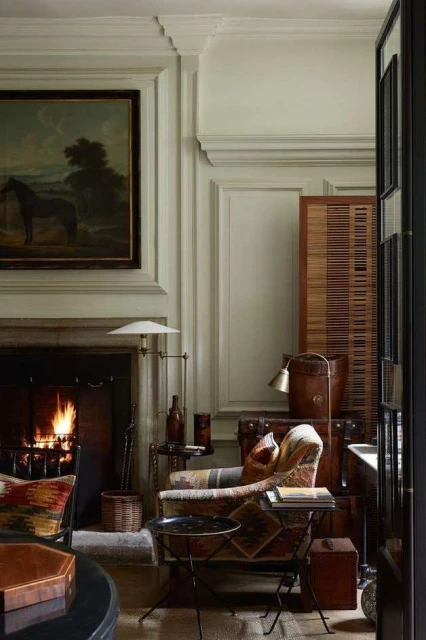 Interior view showcases a patterned armchair and dark accent table, complemented by a burning fireplace and antique-style painting of a horse.