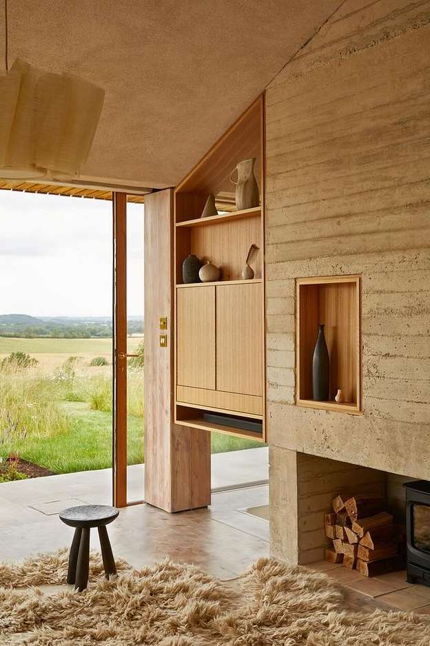 Light wood shelving unit in a modern home interior, showcasing vases and decor, next to a door with a view of a green field.