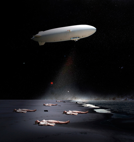 Conceptual image of a blimp over a beach at night, with people laying on the sand and a light shining from the blimp.