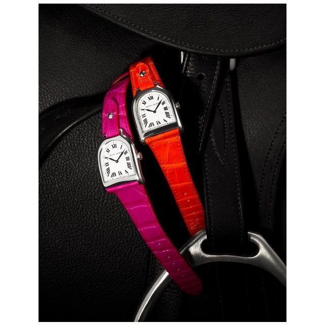 Two colorful watches with orange and pink leather straps resting on a black leather equestrian saddle, product photography.