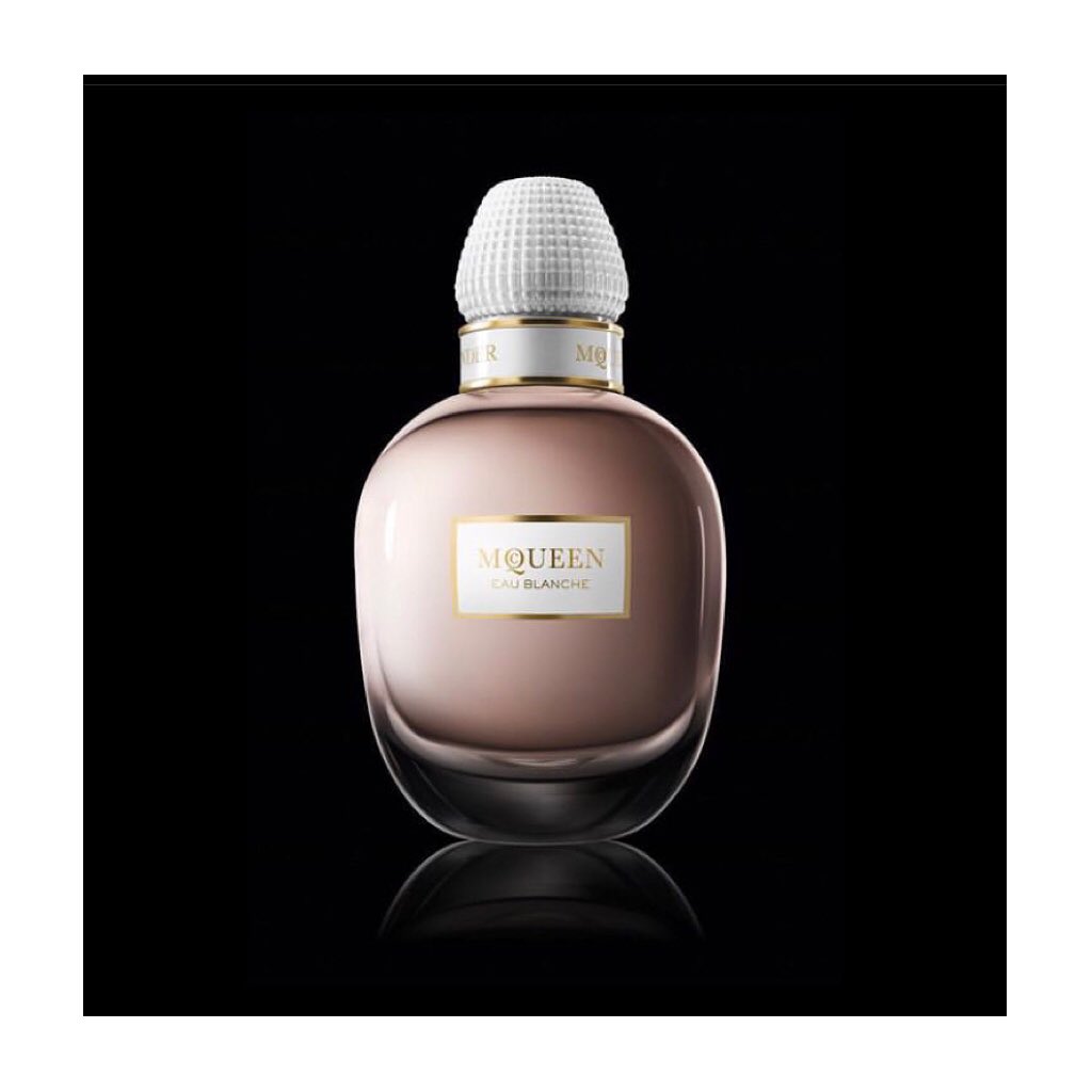 McQueen Eau Blanche perfume bottle against a stark black background, showcasing its elegant design and soft pink hue.