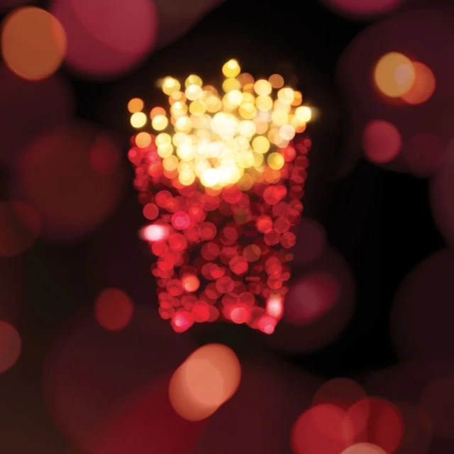 French fries are depicted with red and orange bokeh circles, creating a festive, abstract, and mouthwatering image against a dark backdrop.