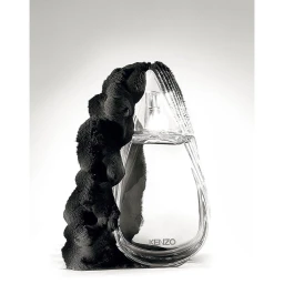 Glass perfume bottle wrapped in textured black fabric against a bright white background, photographed by Helmut Stelzenberger.