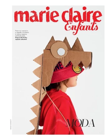 Child in red hoodie wearing a cardboard dinosaur headpiece and a smiley-face hat for Marie Claire Enfants fashion editorial.