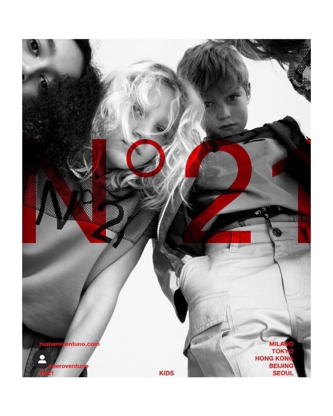 Fashion editorial shot from a low angle featuring two children and two adults in the background, with the brand name 'N21' overlaid in red.