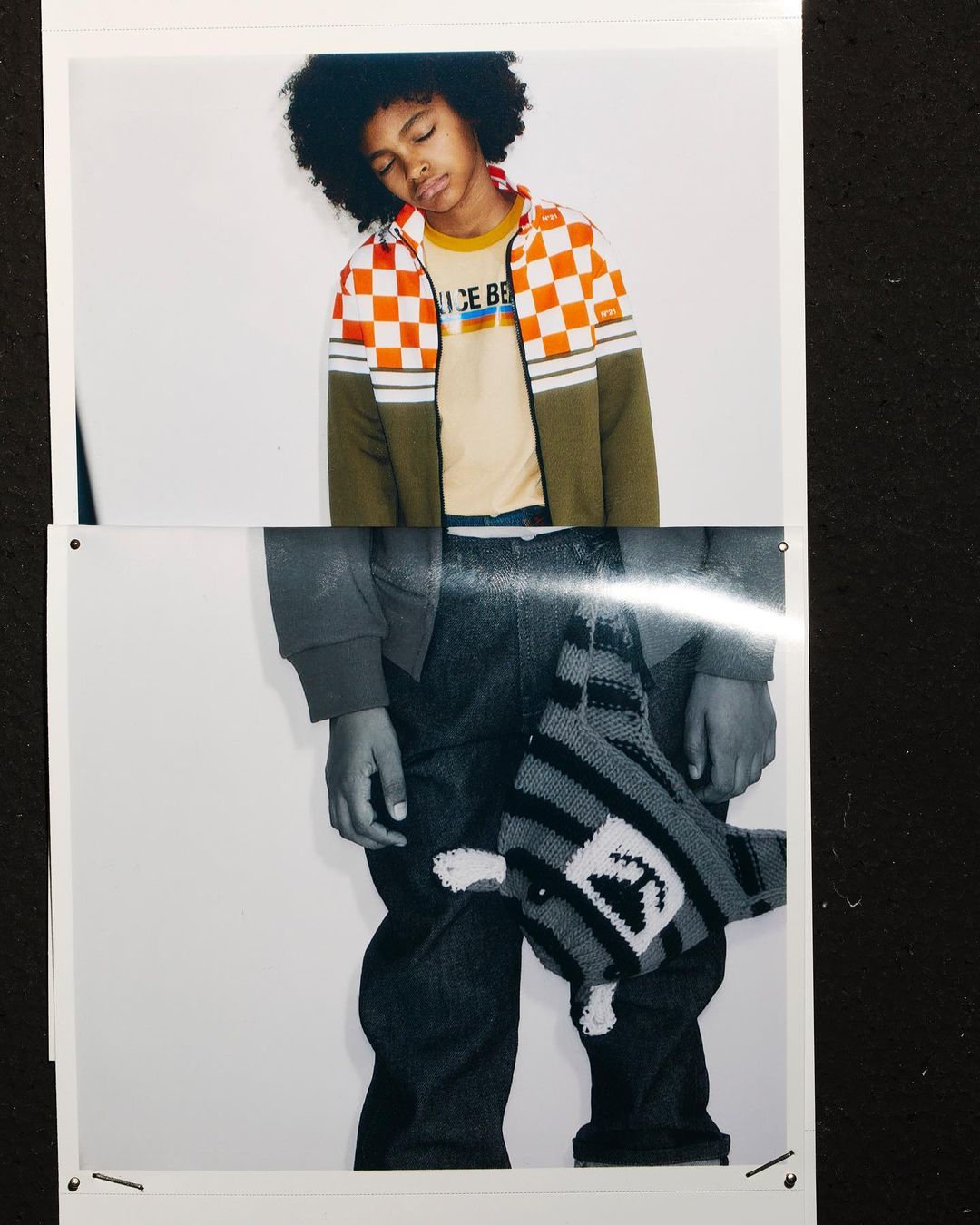 Fashion shot of a young child in casual clothes, wearing a checkered jacket, jeans and a toy hanging from the waist indoors.