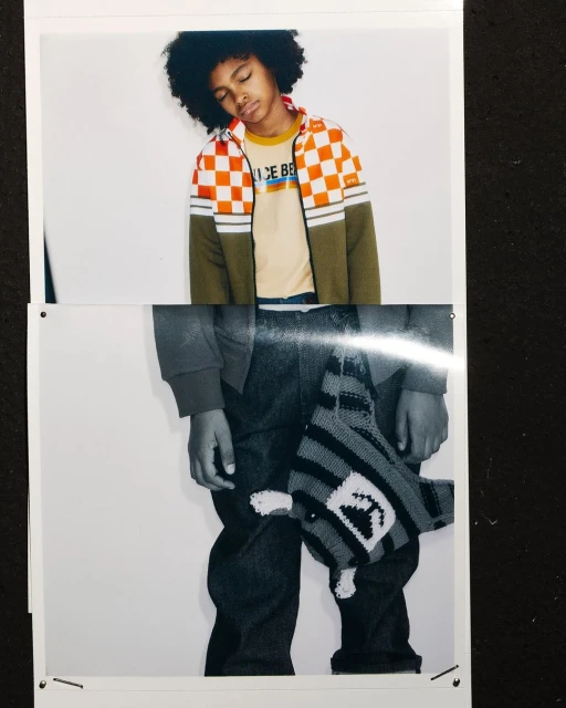 Fashion shot of a young child in casual clothes, wearing a checkered jacket, jeans and a toy hanging from the waist indoors.