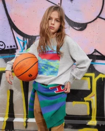 Young child holding a basketball posing against a colorful graffiti wall background