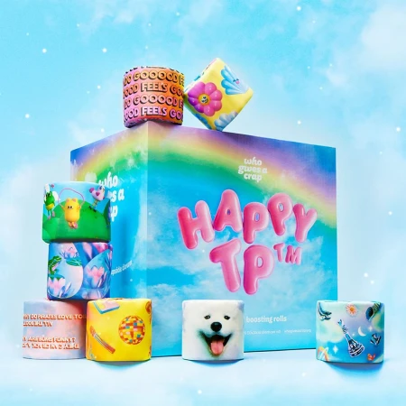 Rolls of colorful, patterned novelty toilet paper stacked against a rainbow-themed box and sky background. Fun, playful, unique designs.