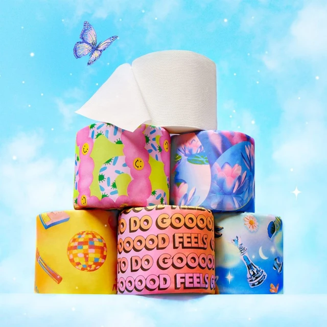 Stack of decorated toilet paper rolls with a butterfly against a light blue cloudy background, studio shot for sustainable products.