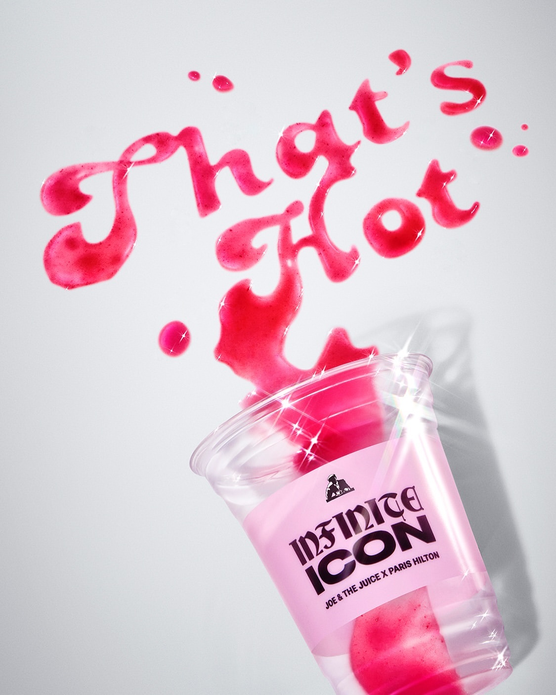 Still life of spilled pink drink with 'That's Hot' script, featuring a branded plastic cup, set against a clean white background.