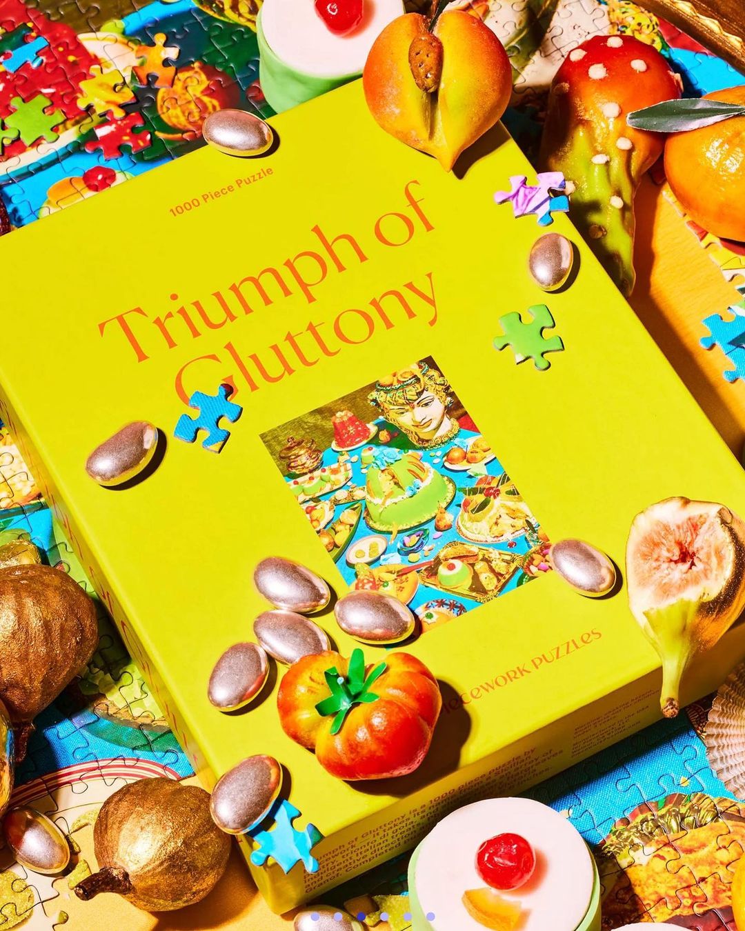 Puzzle box and pieces themed around food, featuring illustrations of various sweet and savory dishes scattered on a patterned surface.