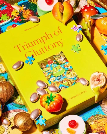 Puzzle box and pieces themed around food, featuring illustrations of various sweet and savory dishes scattered on a patterned surface.