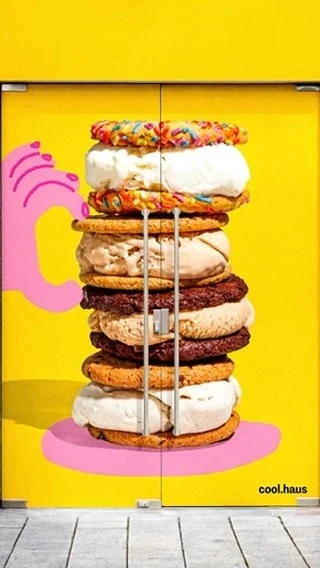 Stack of ice cream sandwiches on a yellow door with a pink hand graphic and a concrete floor. Food and dessert concept.