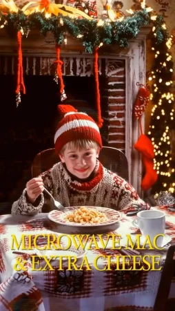A young boy with a red and white knit hat and sweater sits at a table with macaroni and cheese during the Christmas season.