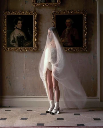 Fashion photography of woman in tulle with vintage portraits. Woman is wearing Mary Jane heels, and white socks in an indoor environment.
