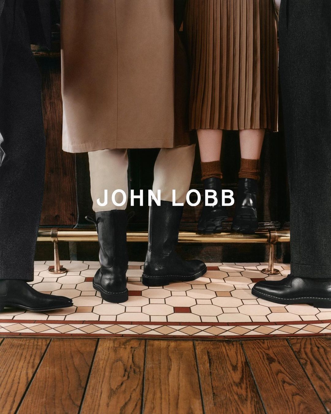 Close-up of three figures in front of a bar, showcasing black John Lobb leather boots and shoes, on a tiled and wood floor.