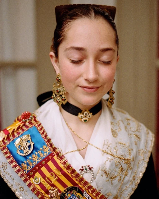 Close-up of a young woman with her eyes closed, wearing traditional attire with ornate jewelry and a colorful sash.