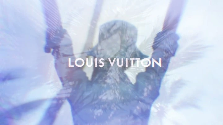 A figure obscured by double exposure and motion, brandishing Louis Vuitton logo, blended with palm fronds in a cool-toned advertisement.