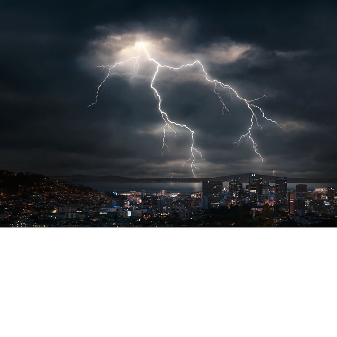 Night cityscape featuring a dramatic lightning storm over illuminated buildings and dark, ominous clouds in the sky. Urban scene.