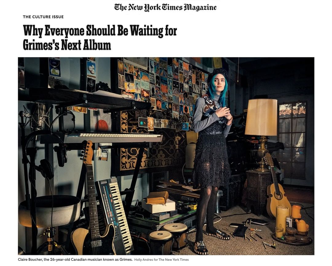 Grimes stands in a room filled with musical instruments and posters for a New York Times Magazine article about her next album.