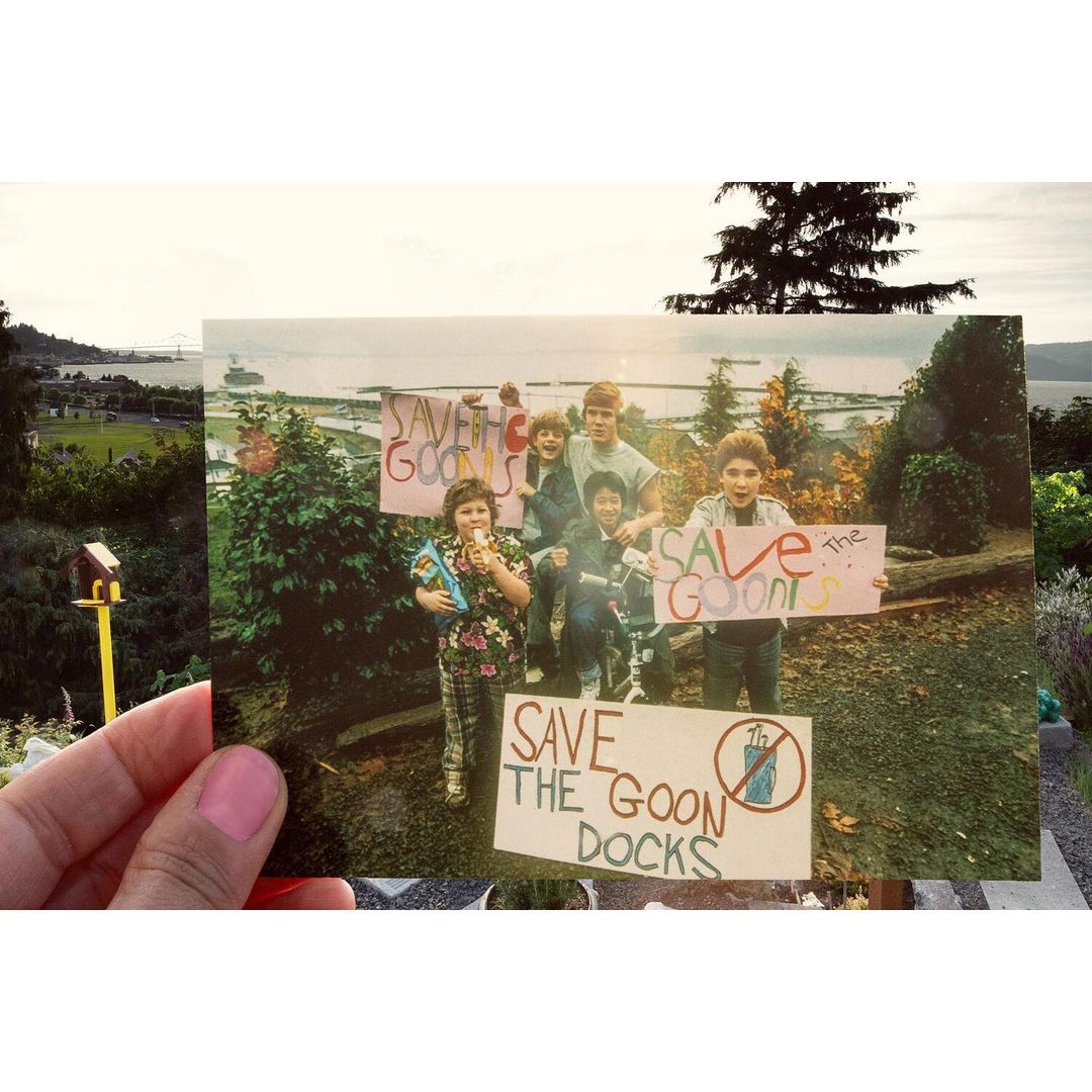 Vintage photo shows group of children holding 'Save the Goon Docks' signs in an outdoor setting, with a cityscape in background.