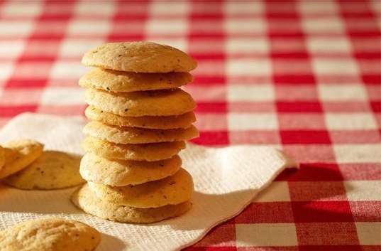 Stack of savory cookies on a white napkin, set against a red and white checkered tablecloth, suggesting a food or snack theme.