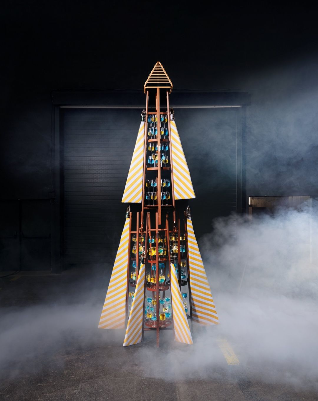 Unique Christmas tree made of bottles and striped fabric in studio setting with fog. Festive, creative, and modern holiday decoration.