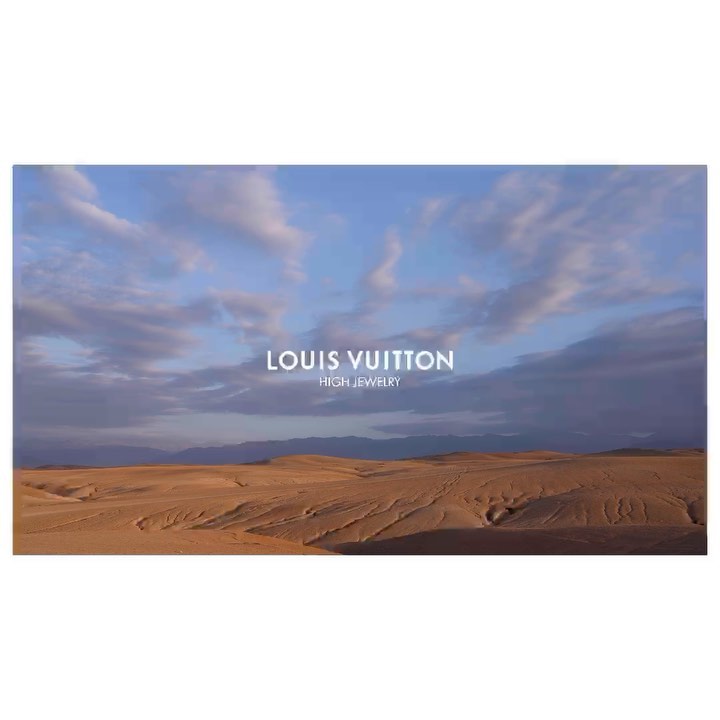 Desert landscape under a cloudy sky with the Louis Vuitton High Jewelry logo prominently displayed in the center of the horizontal frame.