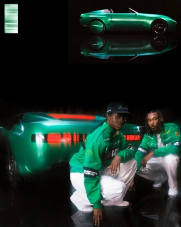 Two young adults in racing-themed jackets squat in front of a green car with black background and smaller car image in the corner.