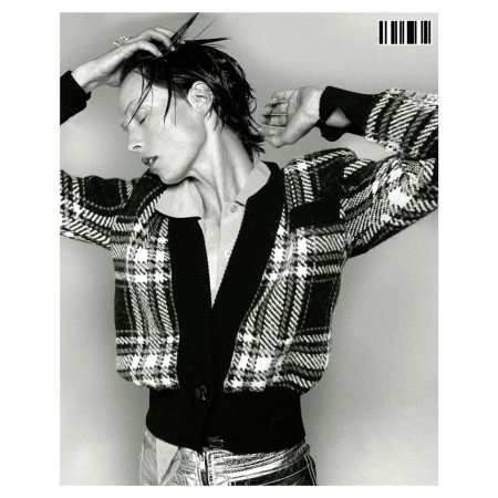 Monochrome portrait of an adult woman in plaid cardigan and metallic pants, with a wet hairstyle against a light gray backdrop.
