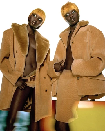 Two dark-skinned fashion models pose in matching tan corduroy coats and bottoms against a white background with a color gradient.