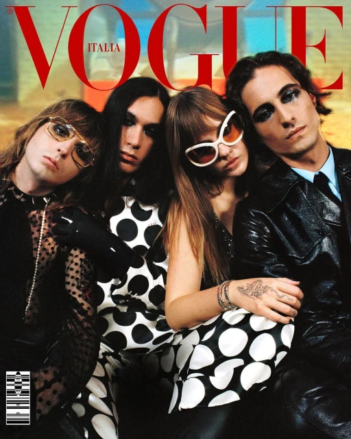 Vogue Italia cover features four people in fashionable clothing, one in a suit, posing indoors with soft lighting and the magazine's logo.