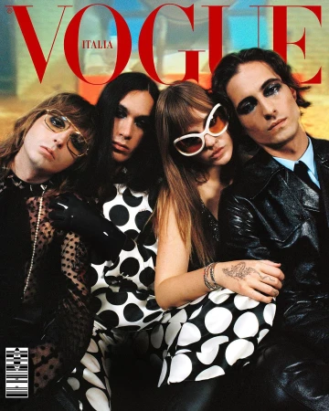Vogue Italia cover features four people in fashionable clothing, one in a suit, posing indoors with soft lighting and the magazine's logo.
