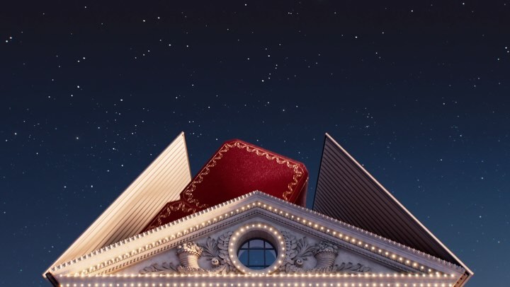 A large red jewellery box rests atop a building façade illuminated by fairy lights, set against a backdrop of a dark blue, star-filled sky.