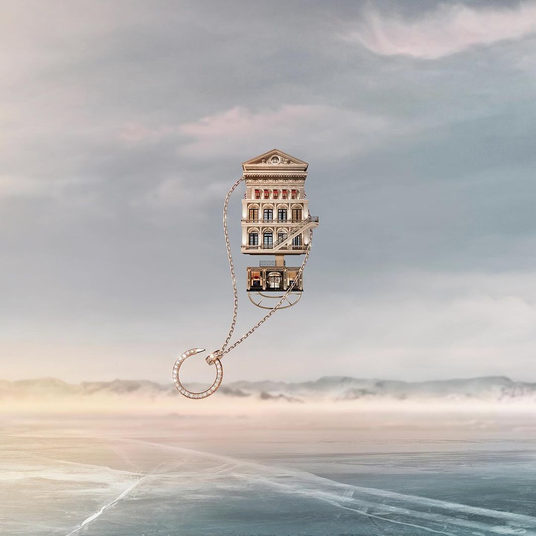 Surreal jewelry advertisement featuring a necklace pendant shaped like buildings over a misty landscape with a hazy sky backdrop.