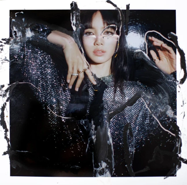 A woman with dark hair in a shiny jacket with paint streaks, fashion photography, studio shot, dark colors, rings and necklace.
