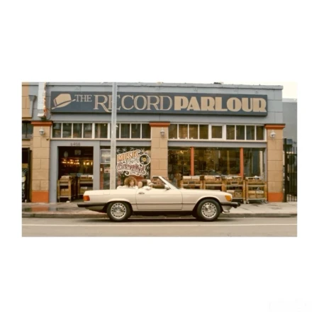 Convertible car parked in front of The Record Parlour store, showcasing the building's exterior, vintage automobile, and signage.