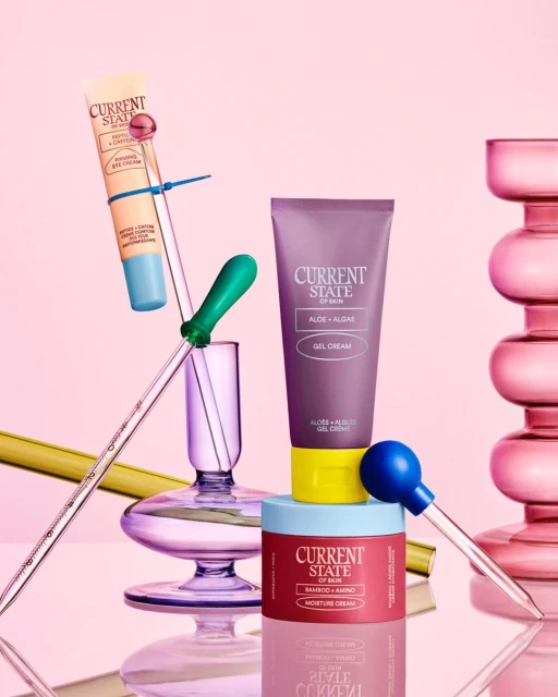 Still life shot of three Current State skin care products stacked on glass pedestals, including eye cream, gel cream and moisture cream.