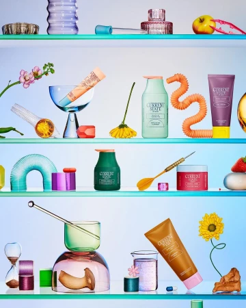 Still life of skincare products from Current State displayed on glass shelves with colorful backlighting and studio lighting. 