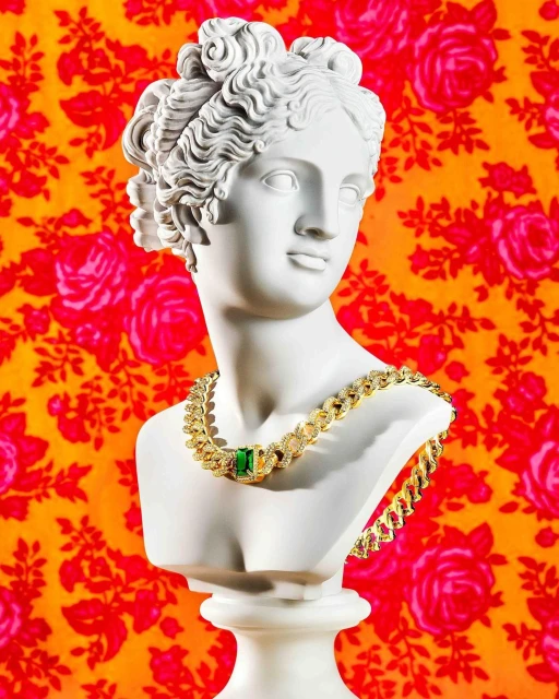 Bust statue of a woman with curly hair and a gold necklace with a large green gem, in front of a flower-patterned orange background.