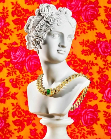 Bust statue of a woman with curly hair and a gold necklace with a large green gem, in front of a flower-patterned orange background.