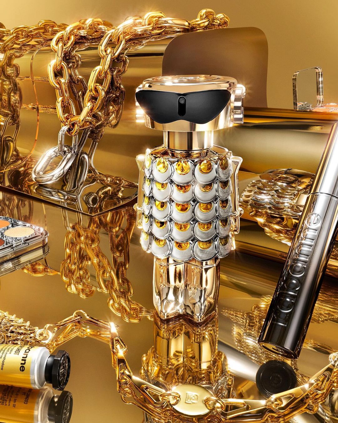 Luxury perfume bottle with gold accents surrounded by gold jewelry and makeup products, showcasing opulence and sophistication in a studio setting.