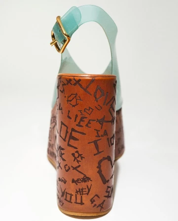 Platform sandal shoe with light-blue straps and brown wooden block heel adorned with handwritten-style inscriptions throughout.