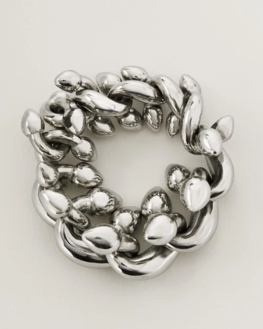 Abstract looping silver chain sculpture on a neutral backdrop with smooth textures, reflective surfaces, and an intricate circular arrangement.