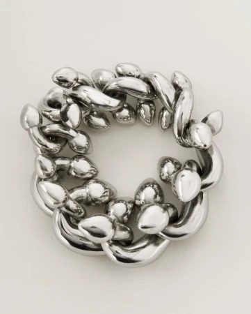 Abstract looping silver chain sculpture on a neutral backdrop with smooth textures, reflective surfaces, and an intricate circular arrangement.