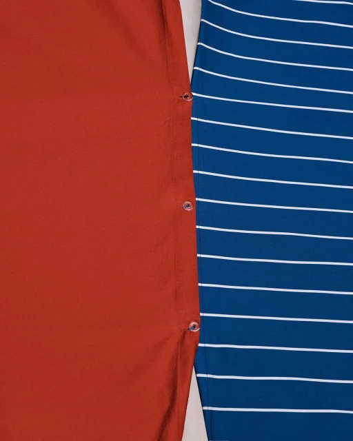 Close-up of two fabrics: a solid orange fabric with button accents next to a blue and white striped fabric.
