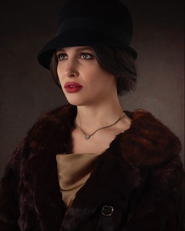 Portrait of a woman in a 1920s-style cloche hat and fur coat, gazing slightly to the left, showcasing a vintage fashion aesthetic.